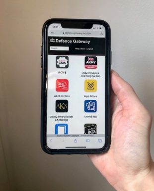 Hand holding a smartphone displaying Defence Gateway applications on the screen