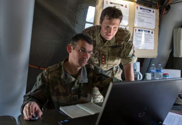 Two male service personnel looking at a laptop screen