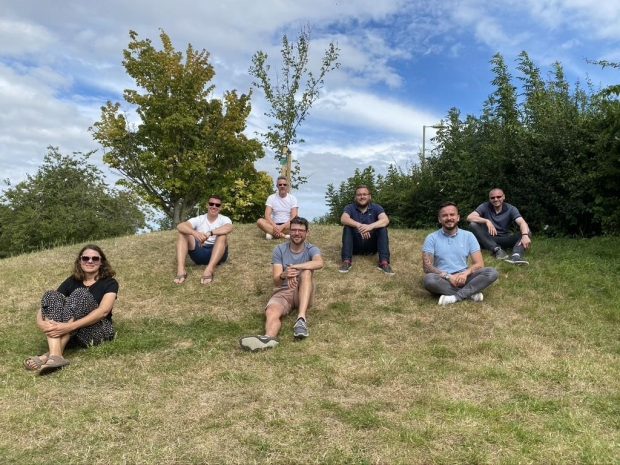 A photograph showing 7 members of the R2-D2 team sat on the grass in a socially distanced manner.